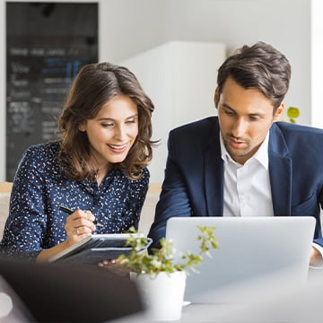 man and woman searching something on computer in a large room