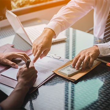 Banker shows person where to sign with money on the other hand Banker shows person where to sign with money on the other hand