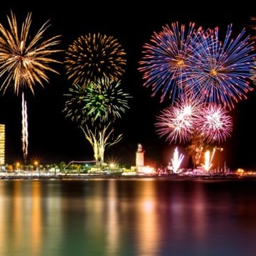 lots of fireworks being fired from city near to sea lots of fireworks being fired from city near to sea