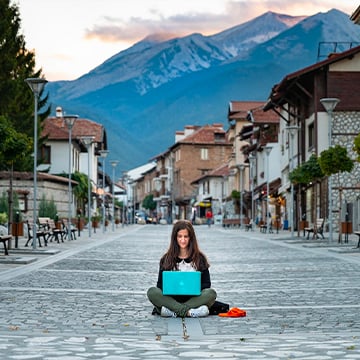 woman sits on street alone with laptop