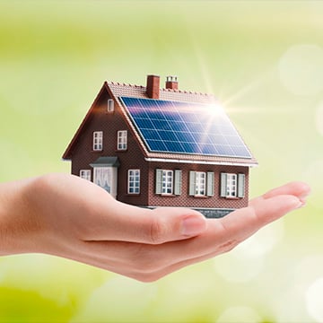 hand holding small house with solar panels on it hand holding small house with solar panels on it