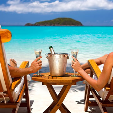 Paar entspannt sich am Strand mit Getränken in den Händen