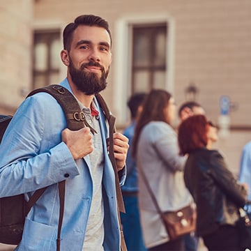 Man with a full beard holding backpack Man with a full beard holding backpack