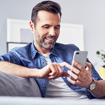 the man smiling while looking at phone the man smiling while looking at phone