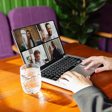 man using laptop for videocall while drinking water