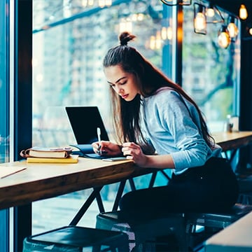woman working on a cafe table with laptop and notepad woman working on a cafe table with laptop and notepad