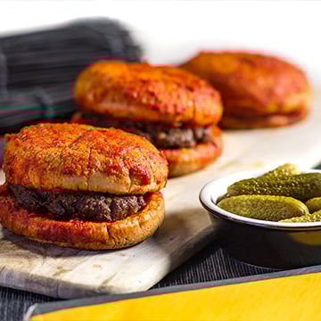 steamed burgers on a wooden plate with pickles on the side steamed burgers on a wooden plate with pickles on the side