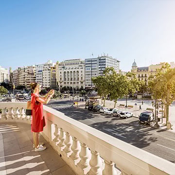 woman in red dress taking photo from balcony